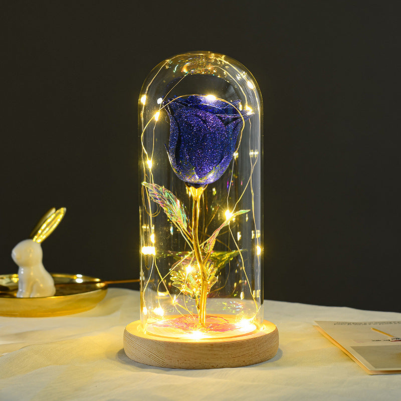 Purple rose in a glass dome with LED lights on a wooden base against a dark background