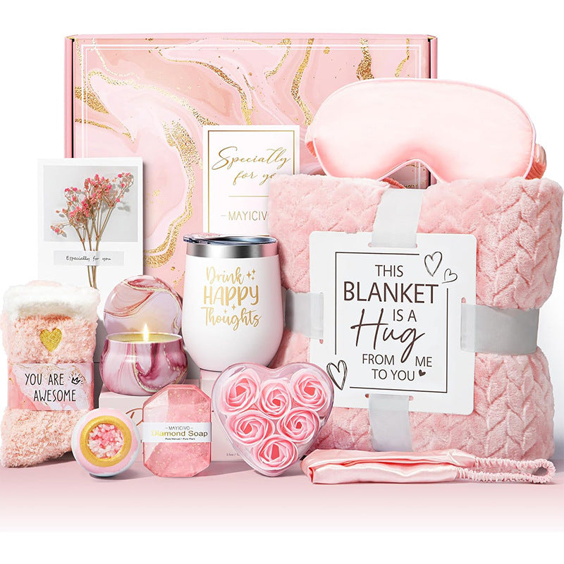 Pink gift set with blanket, candle, and other items on a white background
