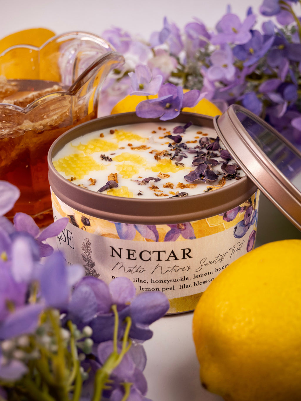 Tub of Nectar body scrub with lemons and flowers in the background