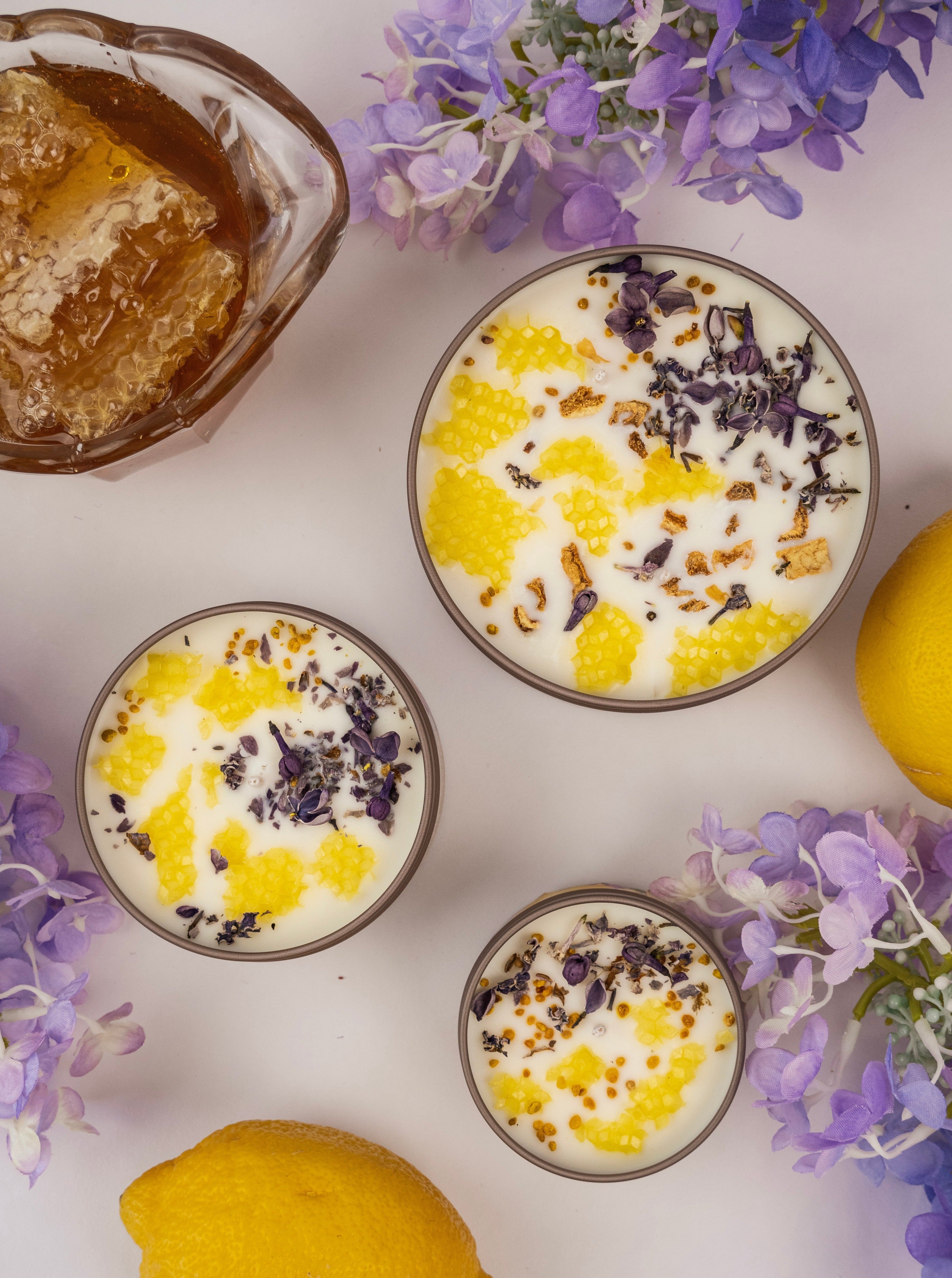 Three small bowls of dessert with lemon and lavender on a white surface with lemons and flowers.