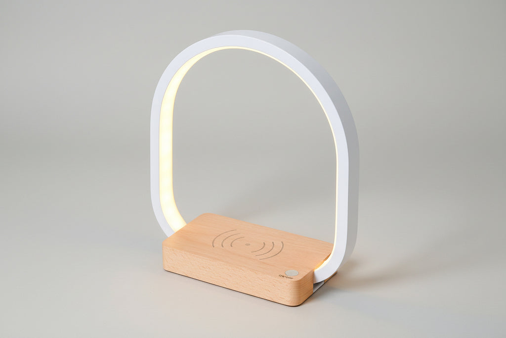 Modern table lamp with wooden base and white arch on a white background