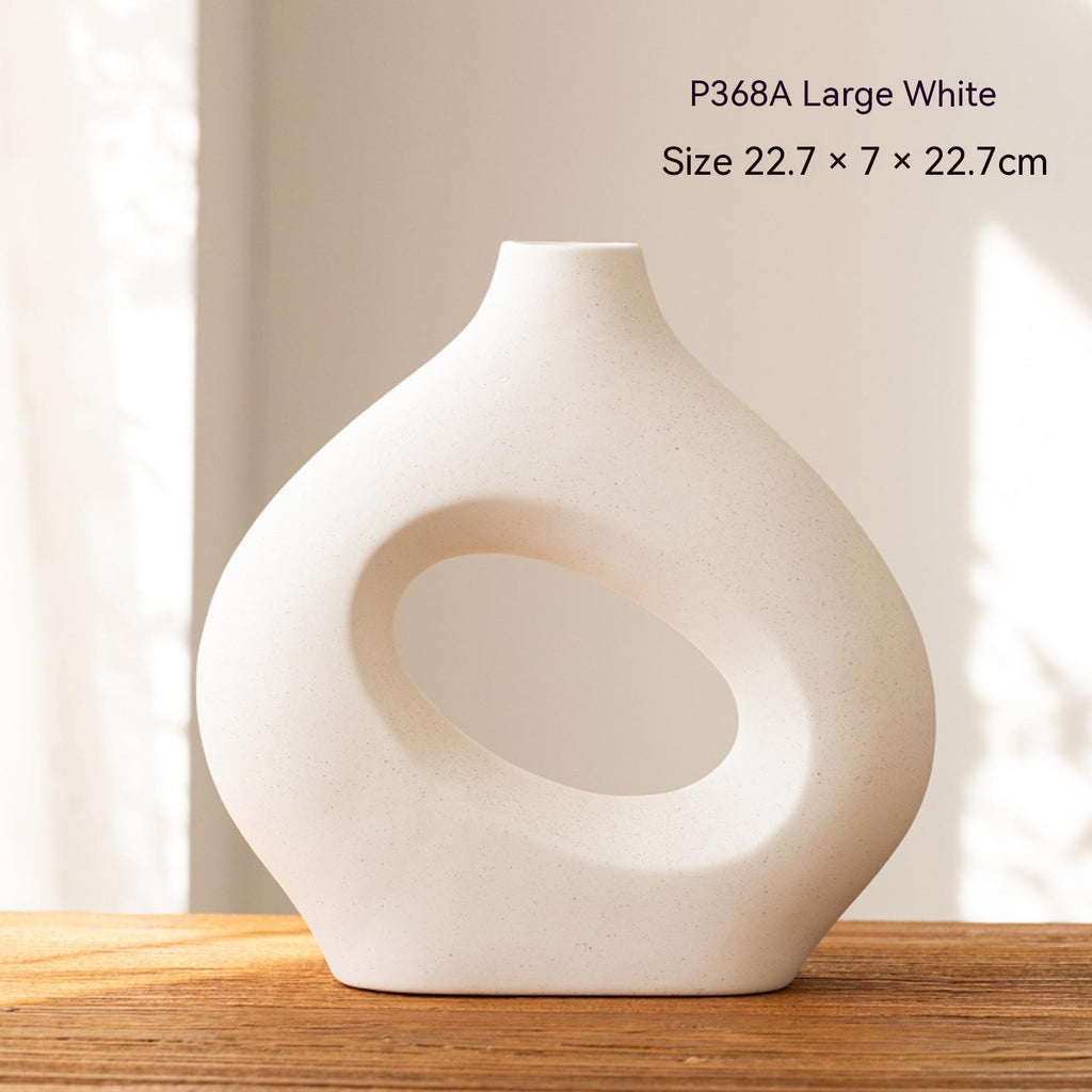 White ceramic vase with a circular design on a wooden surface