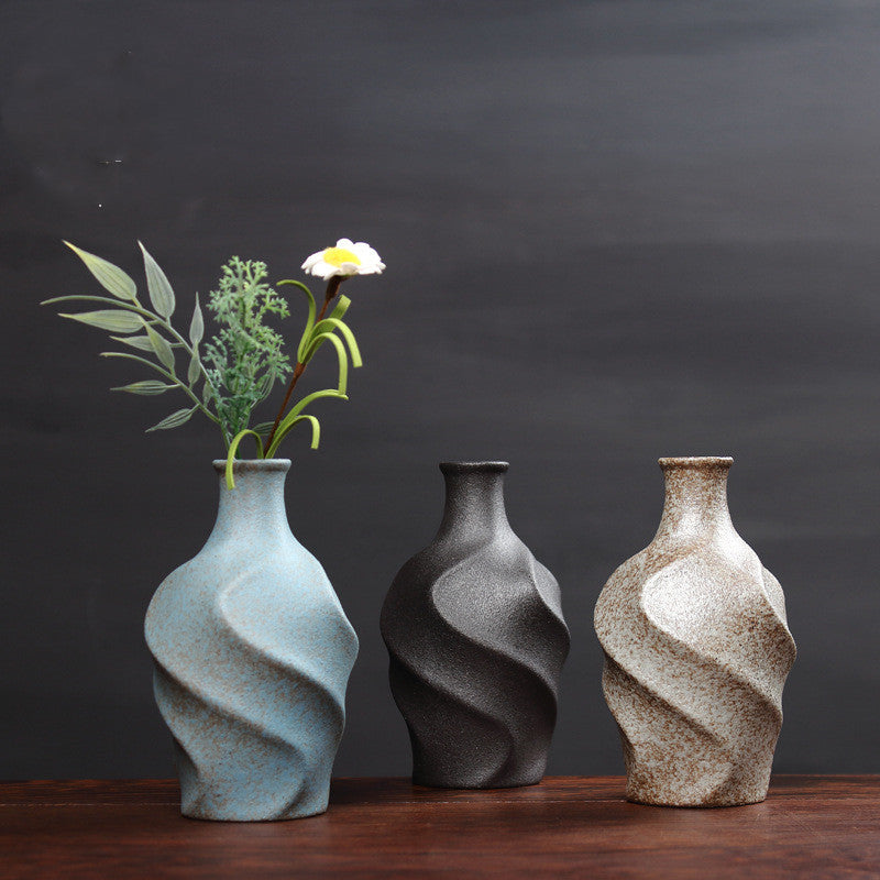 Three ceramic vases with textured surfaces and floral arrangements on a dark background
