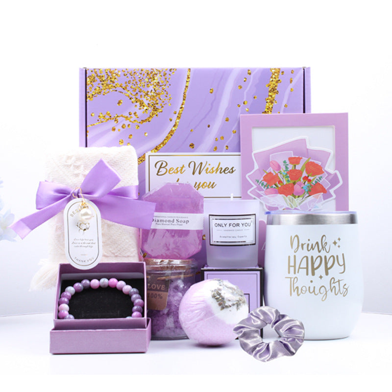 Gifting set with various items including a candle, soap, and bath bomb in a purple box.
