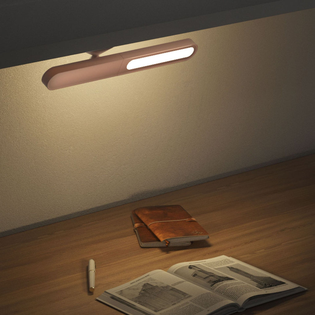 Wall-mounted light fixture on a wall with a wooden surface below containing a notebook and open book.
