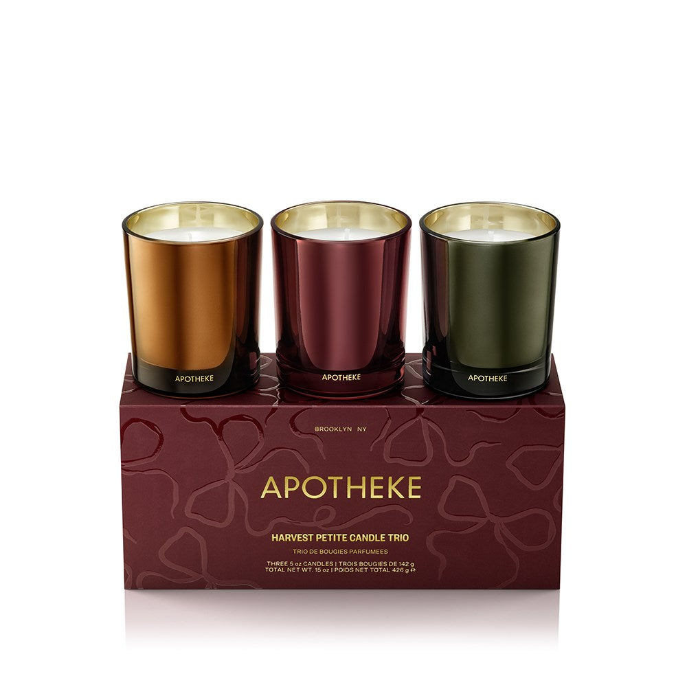 Three Apotheke candles in bronze, gold, and black on a decorative box with 'Apotheke' branding.