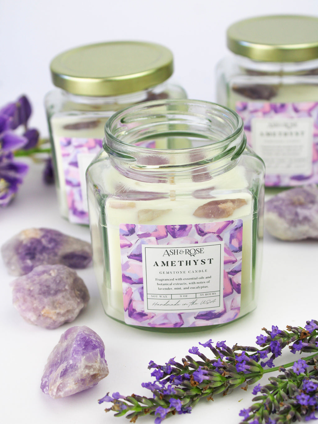 Candle jar labeled 'Amethyst' with lavender flowers and stones on a white background
