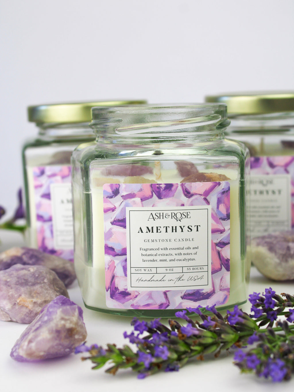 Jar of Ash & Rose Amethyst candle with lavender flowers and crystals on a white background
