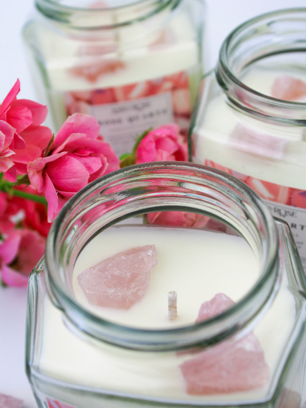 Candle jars with pink flower petals and pink flowers in the background