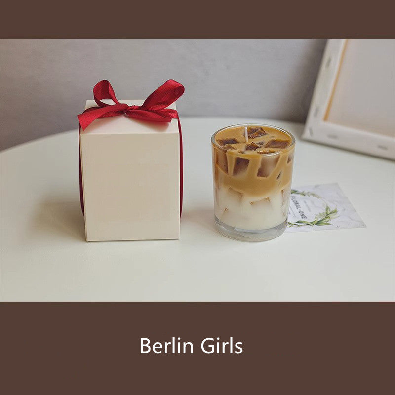 Gift box with a red ribbon next to an iced coffee on a white surface, with 'Berlin Girls' branding.