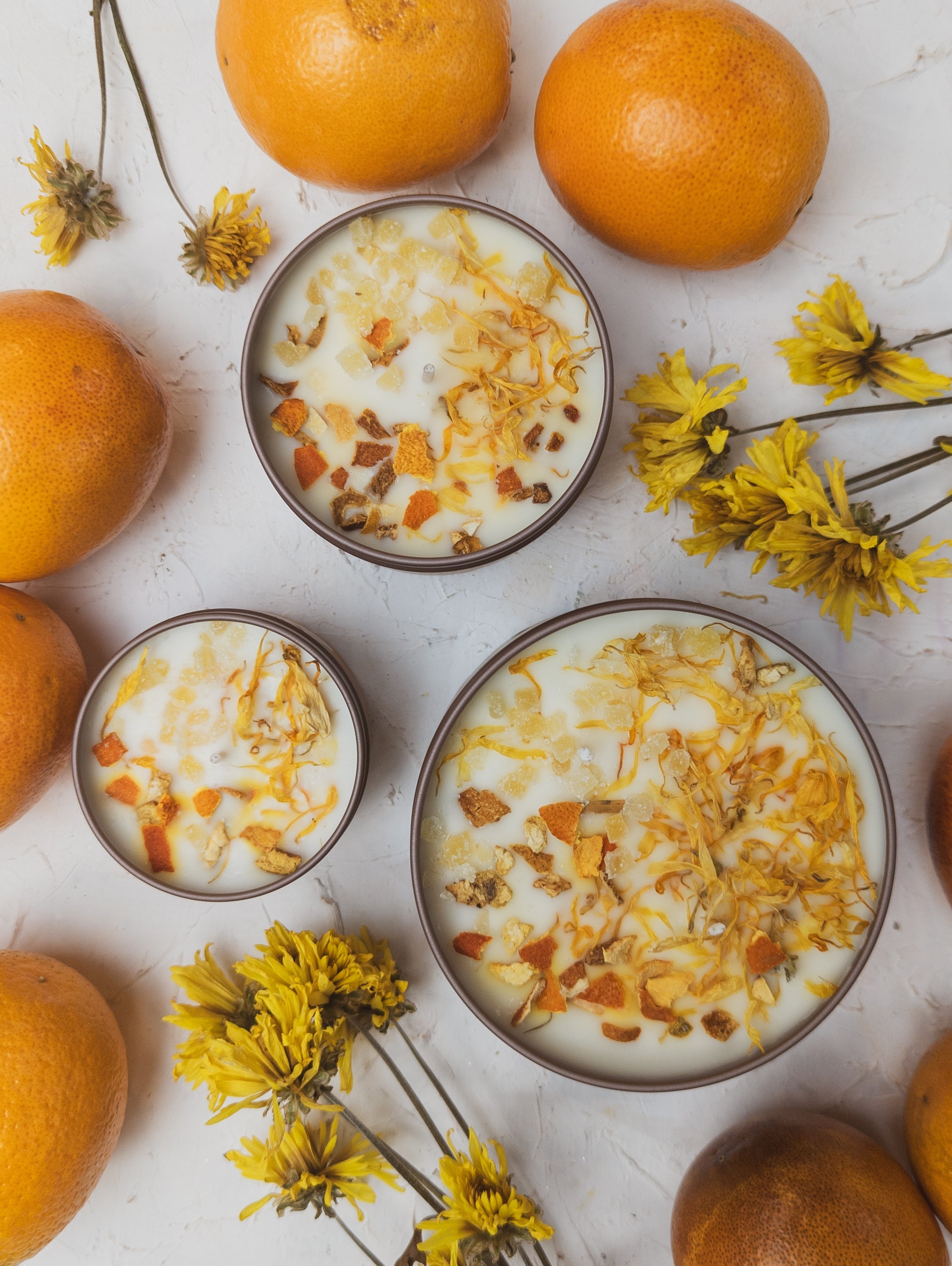 Bowls of yogurt with granola and oranges on a light surface with flowers.