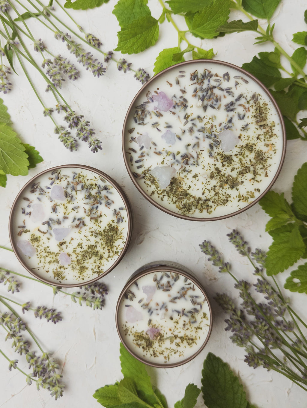 Three bowls of a creamy dessert with lavender and green herbs on a white background with lavender and mint leaves.
