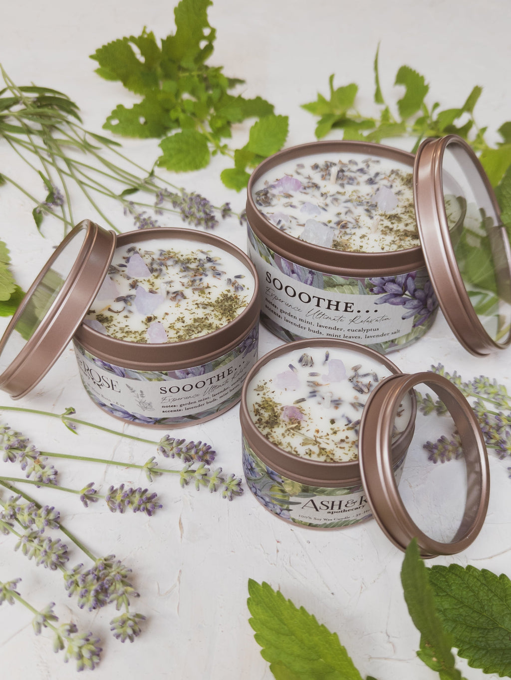 Four tins labeled 'Soothe' with floral labels on a white background with green leaves and lavender flowers.