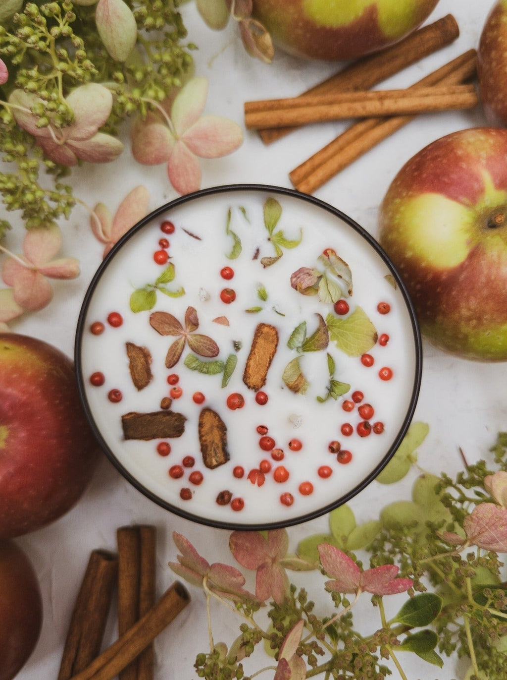 Bowl of candle with fruit and spices on a floral background