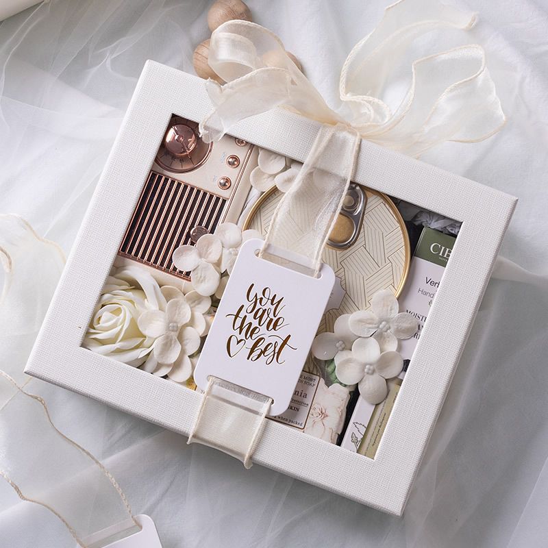 Gift box with decorative items and a tag inside, on a light background