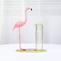 Pink flamingo figurine on a gold stand against a white background