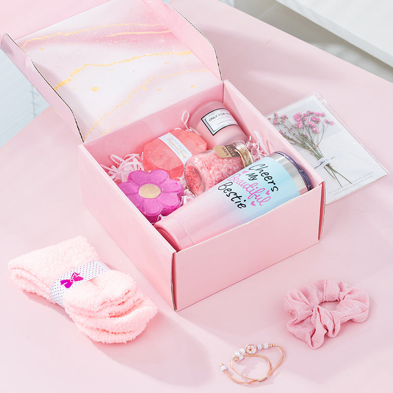 Pink gift box with stationery items on a pink surface