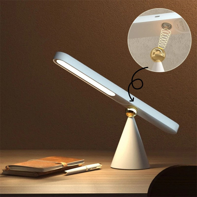Modern desk lamp with adjustable arm on a wooden surface, showing close-up of bulb.