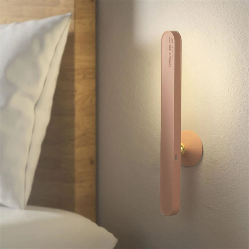 Wall-mounted light fixture on a neutral wall next to a bed