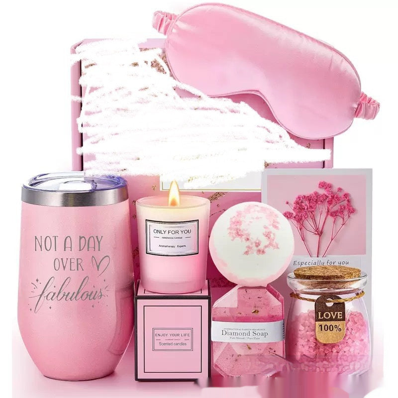 Pink gift set with items including a tumblers, candle, bath bomb, and soap on a white background