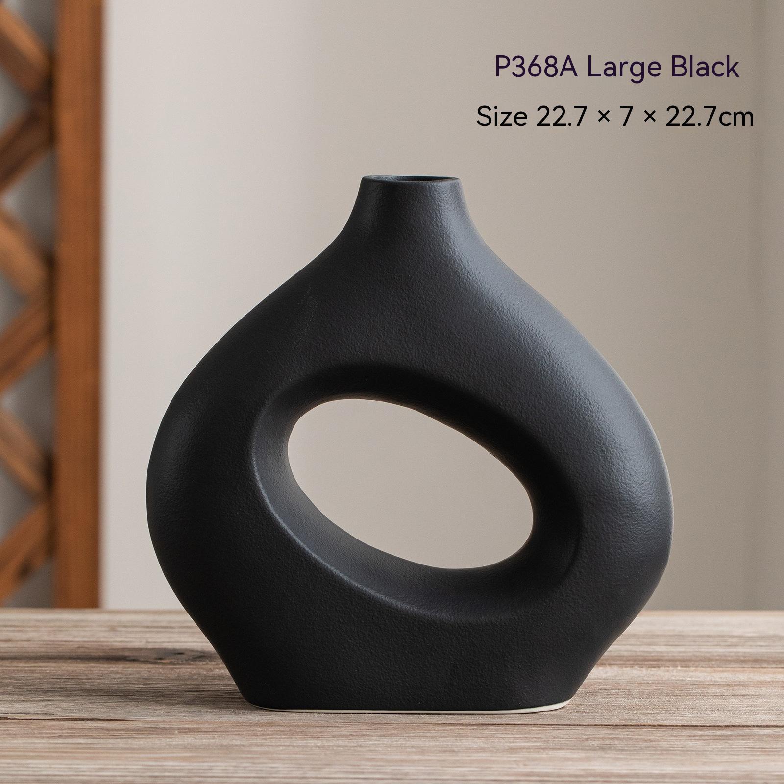 Black vase with circular design on a wooden surface, with text indicating product details.